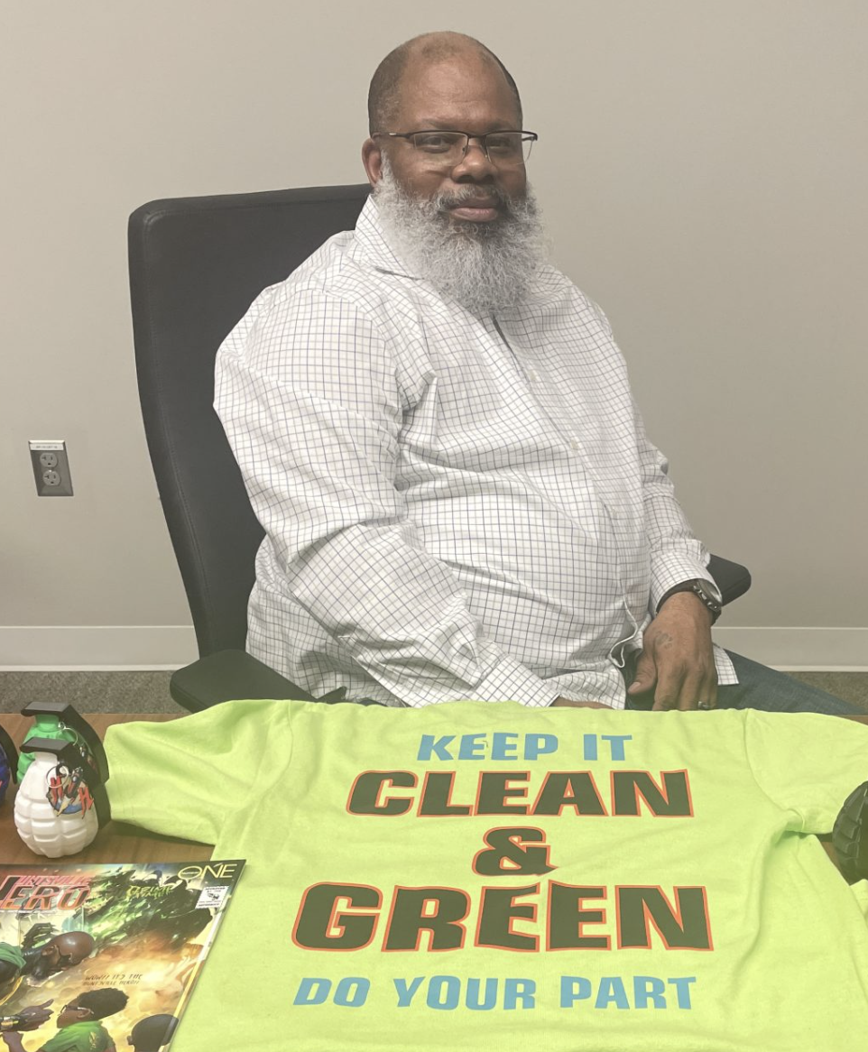 Photo of Erick Wade with sitting next to a tee shirt that says "Keep it Clean and Green - Do Your Part"